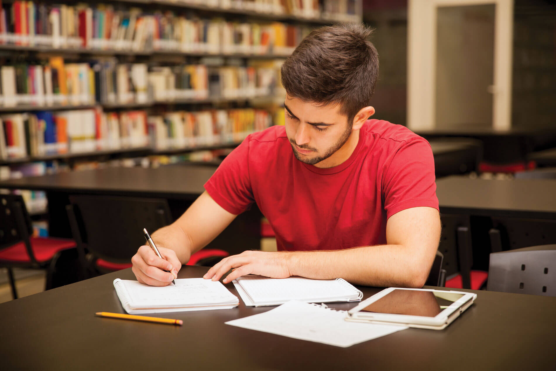 Photo of man at desk, writing.