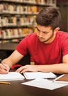 Photo of man at desk, writing.