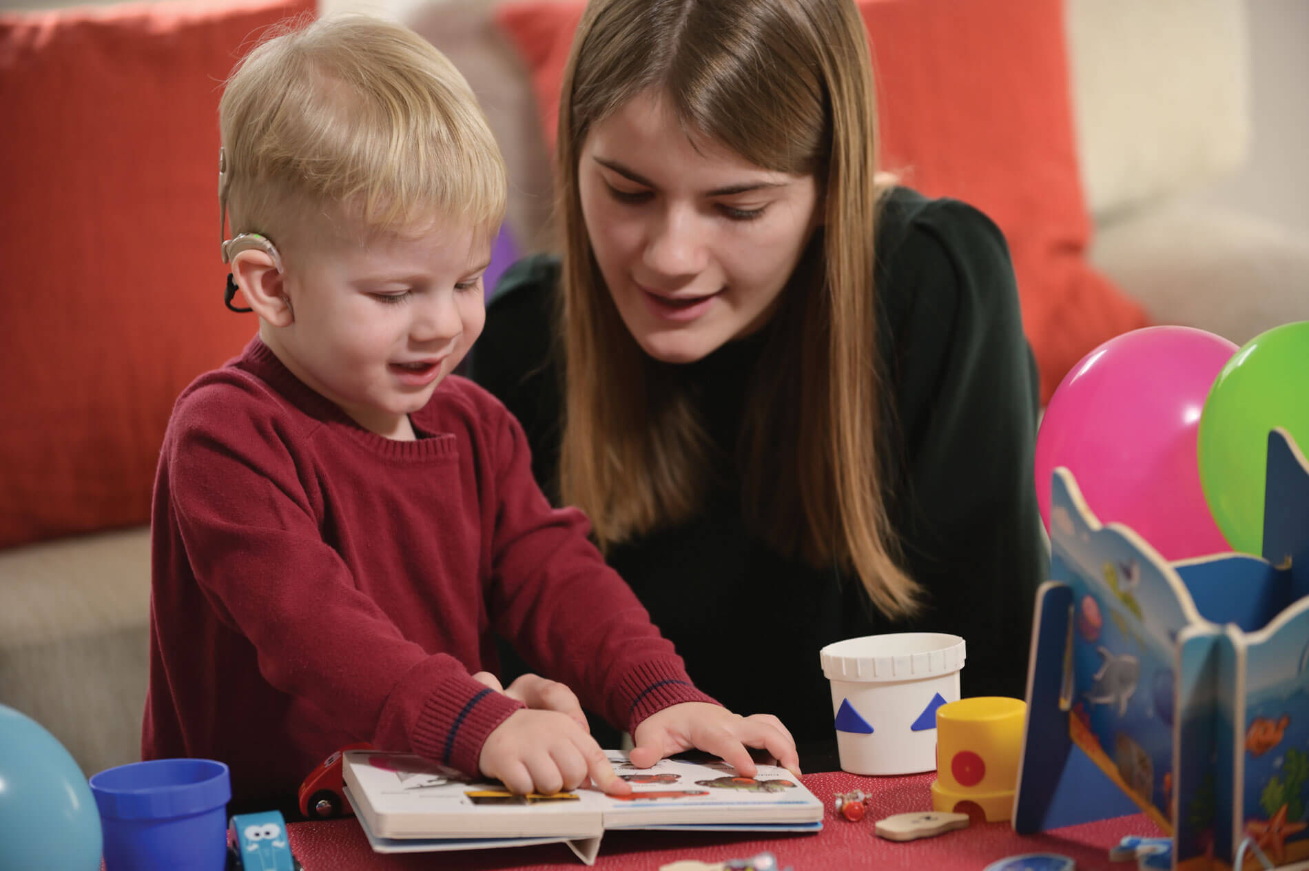 Photo of adult sitting beside child with hearing problems.