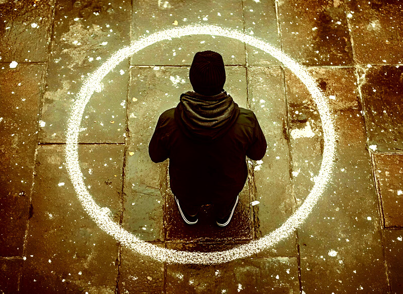 Photo of person standing on pavement.